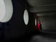A woman wearing a long red dress stands in an empty room being photographed. The Photo app toggles through the focal lengths to demonstrate the capabilities of the pro camera system, showcasing: 35 mm