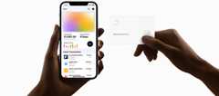 One hand holding an iPhone with financial information on screen and other hand holding an Apple Card
