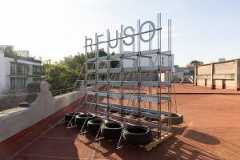 A rooftop installation at Reuse: Architectures of Almost Nothing consisting of tires and metal that spells out Reuso.