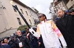 Snoop Dogg holding an official 2026 Winter Olympics torch designed by Carlo Ratti Associati