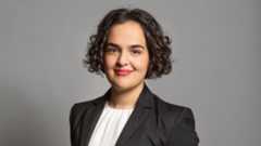 a head and shoulders shot of Nadia in white top and grey blazer with hair down