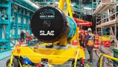 The immense digital camera is slowly being moved into place lifted by a yellow lift.