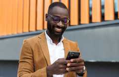 Confident African American businessman using smart phone in urban setting