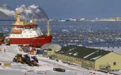 A landscape of an Antarctic base with a large ship docked nearby