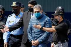 Trump_Hernandez_Pardon_83824 FILE – Former Honduran President Juan Orlando Hernandez, second from right, is taken in handcuffs to a waiting aircraft as he is extradited to the United States, at an Air Force base in Tegucigalpa, Honduras, April 21, 2022. (AP Photo/Elmer Martinez, File)