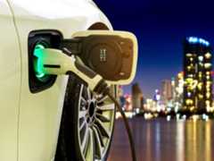 Electric vehicle charger with city skyline at night.