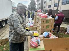 ABN-L-TURKEYGIVEAWAY-1127-01 Saul Fultz, who lives at Maple Terrace Apartments in Aurora, volunteers to help give away free Thanksgiving meal boxes on Monday at the apartment complex as part of an Aurora Housing Authority holiday distribution effort. (David Sharos/For The Beacon-News)