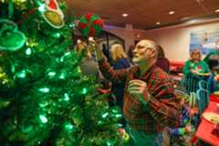David Sebolka, of Harveys Lake and representing Ava’s Toy Box, hangs an ornament on a Christmas tree during the annual Grotto Pizza Parade of Trees in Harveys Lake on Tuesday, Nov. 25, 2025. (JASON ARDAN / STAFF PHOTOGRAPHER)