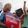 protesters hold up signs protesting cuts to Medicaid