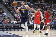 Denver Nuggets center Nikola Jokic, left, looks to pass the ball as Los Angeles Clippers center Ivica Zubac and guard James Harden, right, defend in the first half of an NBA basketball game Friday, Dec. 13, 2024, in Denver. (AP Photo/David Zalubowski)