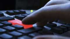 Computer keyboard with red enter key being pressed