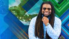 A Black man wearing sunglasses smiles, in front of a colorful background