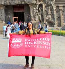 A young woman holds up an FDU flag on a trip to India in 2019.