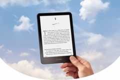 A hand holding a Kindle e-reader against a cloudy sky background, resized to a 16:9 aspect ratio.