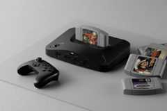 A black Nintendo 64 console with a game cartridge inserted, a black controller, and several other game cartridges scattered nearby, all on a light gray surface with a subtle geometric pattern.