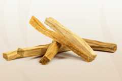 Several palo santo wood sticks are arranged on a soft, gradient background, presented in a 16:9 aspect ratio.