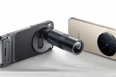 A black smartphone with an attached telephoto lens and a gold smartphone with a large circular camera module, both lying on a white surface.