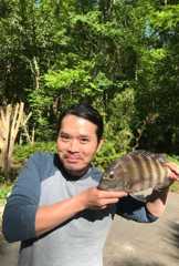 man standing outside holding a fish