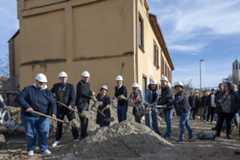 Viele Menschen mit einem Spaten und einem Helm werfen Sand in Richtung der Kamera