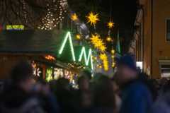 Weinachtsmarkt mit beuleuchtenten Ständen und unscharfen Menschen im Hintergrund