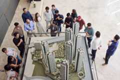 A group of students gathered around an architectural model of skyscrapers