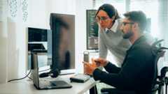 woman and man review multiple screens with programming code