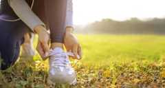 young woman runner tying her shoes preparing for a jog outside at morning