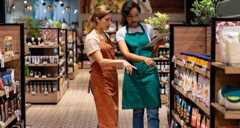Business manager training a new retail clerk at a supermarket