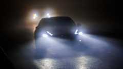 Two cars driving at night on a foggy road