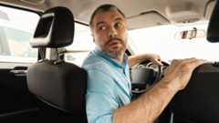 A person driving in reverse in their car while looking over their shoulder