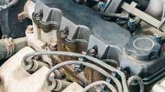 Old four-cylinder car engine with visible oil stains on the valve cover.