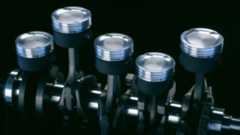 An inline five-cylinder engine's pistons, connecting rods, and crankshaft make up the rotating assembly that's floating in a black void background