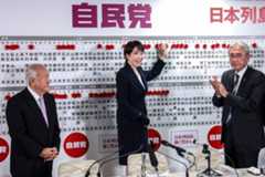 Prime Minister Sanae Takaichi, who also serves as president of the Liberal Democratic Party, stands next to LDP Secretary-General Shunichi Suzuki (left) and party Election Strategy Chief Keiji Furuya, placing a red paper rose on the name of an elected candidate at LDP headquarters in Tokyo during the Lower House election on Sunday.