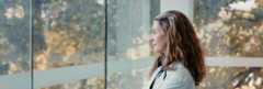 Female doctor looking out a window at nature.