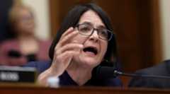 A photo of Balint speaking with her hand raised into a microphone.