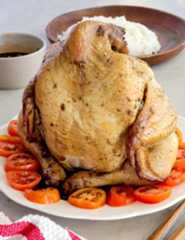 Pinaupong Manok on a white serving platter over sliced tomatoes.