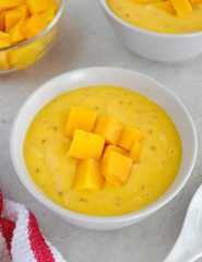 Mango tapioca dessert in a white bowl topped with fresh mango cubes.