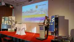 Axel Kullick am Rednerpult neben einer Präsentationswand