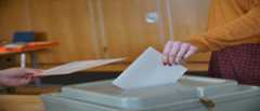 Stimmzettel wird in eine Wahlurne eingeworfen