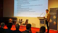 Bürgermeister Heiko Rosenthal steht am Rednerpult auf der Bühne und spricht zum Publikum. Im Hintergrund ist seine Präsentation eingeblendet