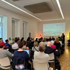 Viele Menschen sitzen im Publikum vor einer Leinwand. Darauf werden die Ergebnisse gezeigt.