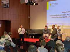 Bürgermeister Heiko Rosentahl steht mit Mikrofon in der Hand neben der Bühne und beantwortet eine Frage aus dem Publikum.