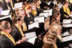 Die Sängerinnen des Mädchenchores singen und halten Notenblättern in ihren Händen