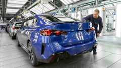 Ein Mitarbeiter des BMW Werks Leipzig mit einem in Leipzig gefertigten Auto in einer Werkshalle