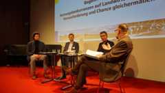 Auf der Bühne sitzen vier Männer und diskutieren miteinander.