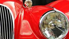 Oldtimerkennzeichen Scheinwerfer und Teil der Motorhaube eines roten Oldtimer-Autos