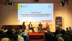 Auf der Bühne sitzen vier Männer und diskutieren miteinander.