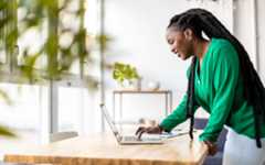 A woman standing at a desk in an office while using her laptop.