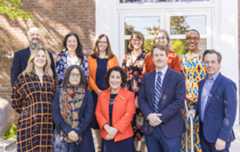 Portrait of Macalester's Senior Leadership team. The team has 11 members, and they are all dressed in blue and orange apparel.