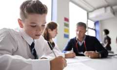 School children writing in a classroom.